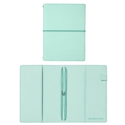 A mint green leather planner cover shown in two views: closed with an elastic band, and open with a pen loop holding a pen, on a white background. The brand 'rock paper studio' is printed in the bottom right corner of the open cover.