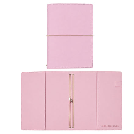 A pink faux-leather planner or notebook set shown in two views: closed with an elastic band at the top, and open at the bottom to reveal interior pockets and a pen loop. The brand name 'rock paper etude' is printed in the bottom right corner of the open cover.