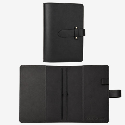 A black leather planner or notebook cover shown in two views: closed with a strap closure at the top, and open to reveal interior pockets and a strap tab on the right side. The brand name 'rusty russia studio' is subtly printed in the bottom right corner of the open cover.
